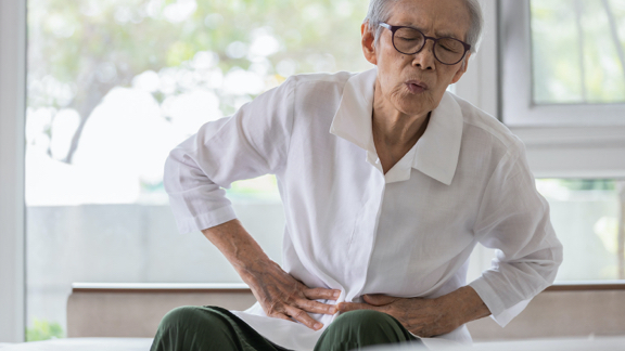 Man clenching waist with gastric discomfort.