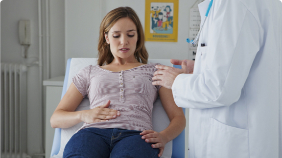 Female patient with stomach discomfort getting medical examination.