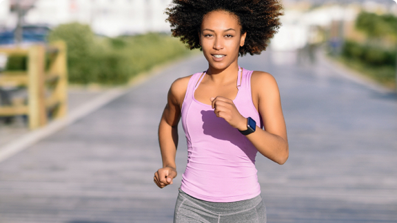 Female in activewear running outside in a city.