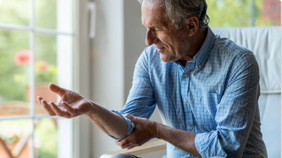 Elderly man with joint pain holding his elbow.